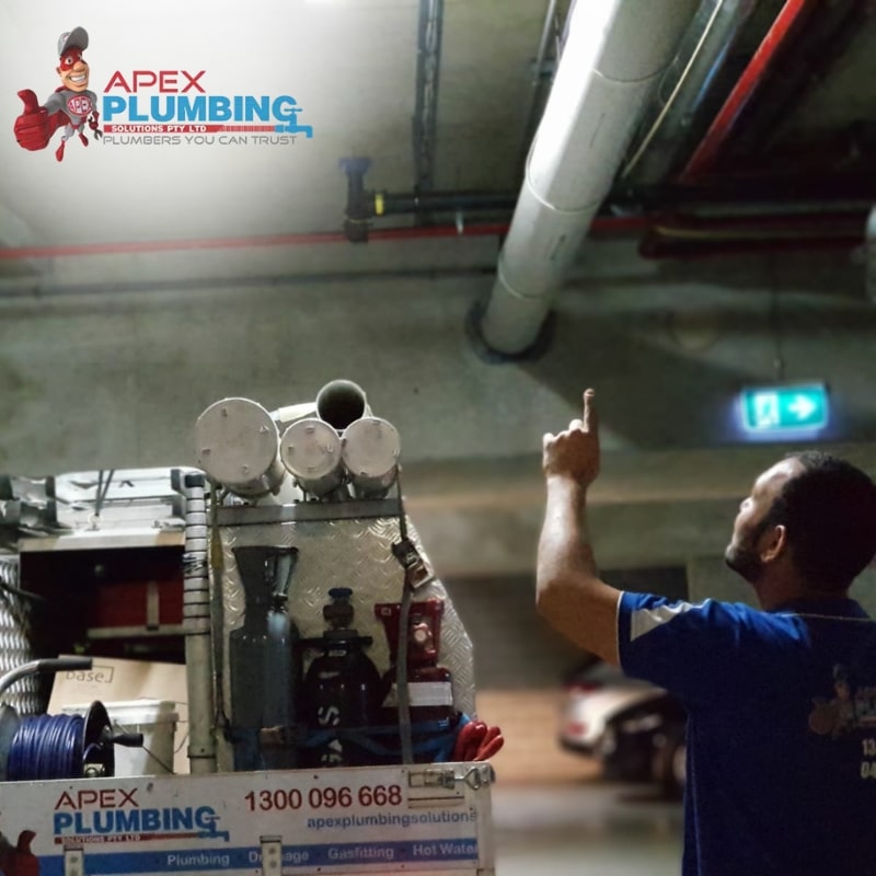 A licensed plumber from Apex Plumbing Solutions fixing a damaged pipe using pipe lining techniques.