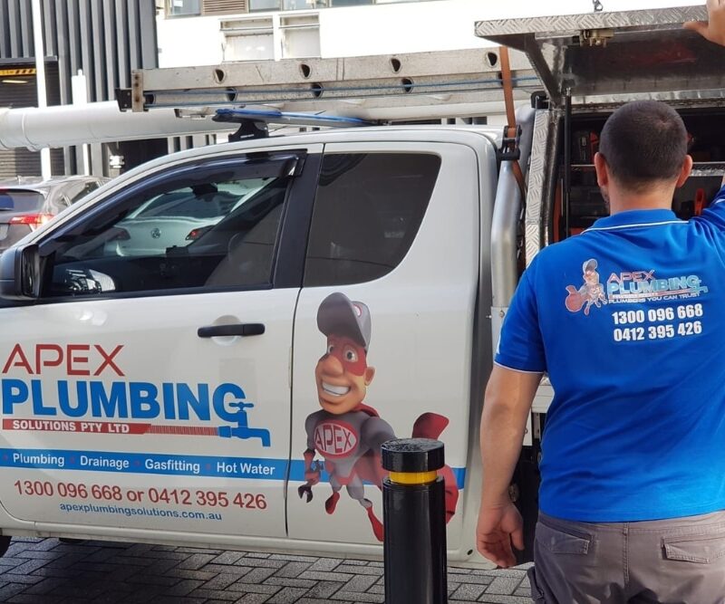 A professional plumber standing beside a truck labeled "Apex Plumbing Solutions Pty Ltd," preparing for a job. This image emphasizes the importance of knowing when to call a professional for issues such as how to unclog a toilet without a plunger.