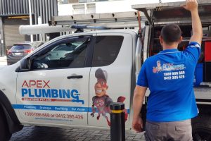 A professional plumber standing beside a truck labeled "Apex Plumbing Solutions Pty Ltd," preparing for a job. This image emphasizes the importance of knowing when to call a professional for issues such as how to unclog a toilet without a plunger.