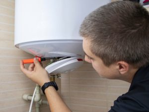 Technician repairing a water heater, addressing issues that can lead to low hot water pressure.