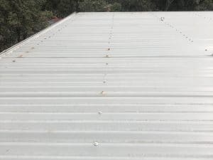 Metal roof with screws checked to prevent potential leaking roof damage in residential property.