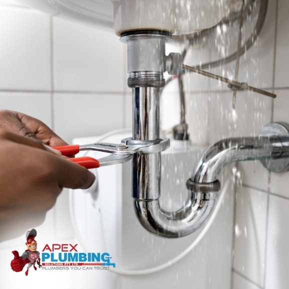 Pipe Repair Service For Fast Results: A plumber is using pliers to fix a leaking pipe under a sink.