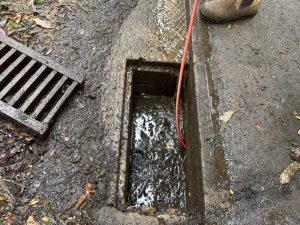 A clogged stormwater drain with a red hose clearing the blockage. Are flushable wipes actually flushable in drains?