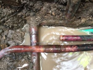Damaged and corroded underground rusting pipes leaking water, highlighting the risks of untreated pipe deterioration.