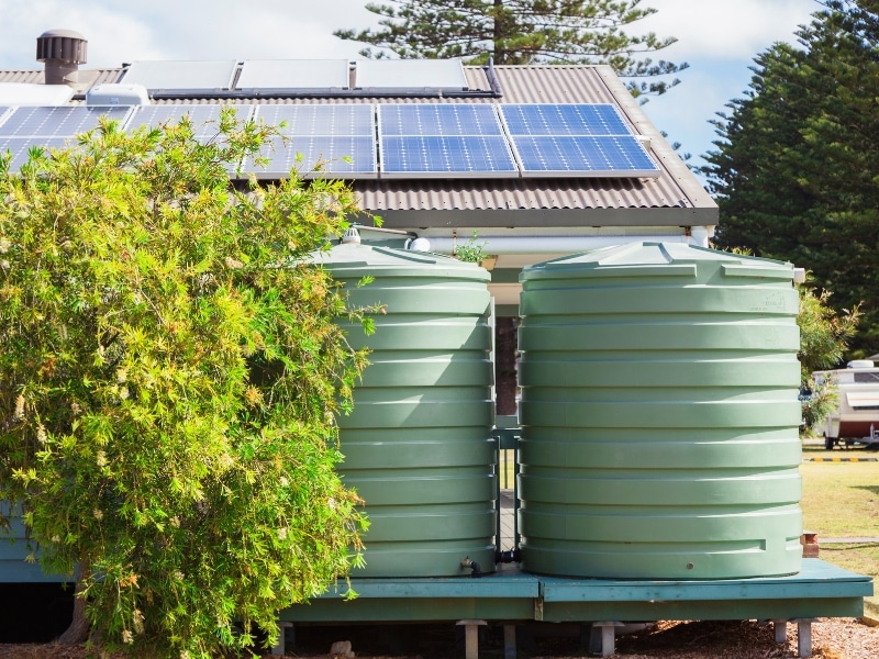 house water tanks green plastic tanks behind home with solar panels