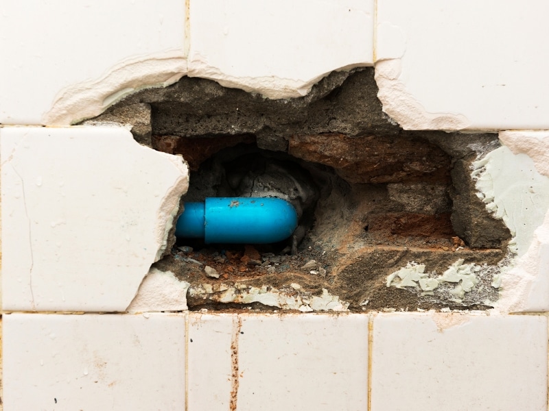 Leak detection solution inspecting damaged wall exposing blue water pipe.