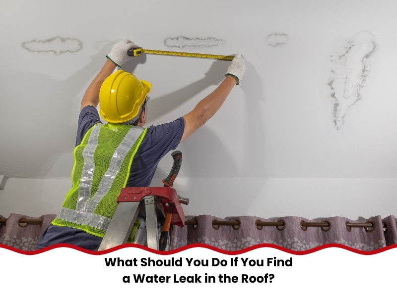 Water Leak in the Roof inspection: tradesperson measuring stain size on ceiling from ladder wearing hard hat.