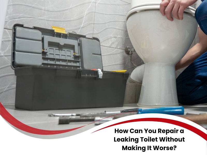 Plumber using tools to repair leaking toilet beside an open toolbox in a tiled bathroom.