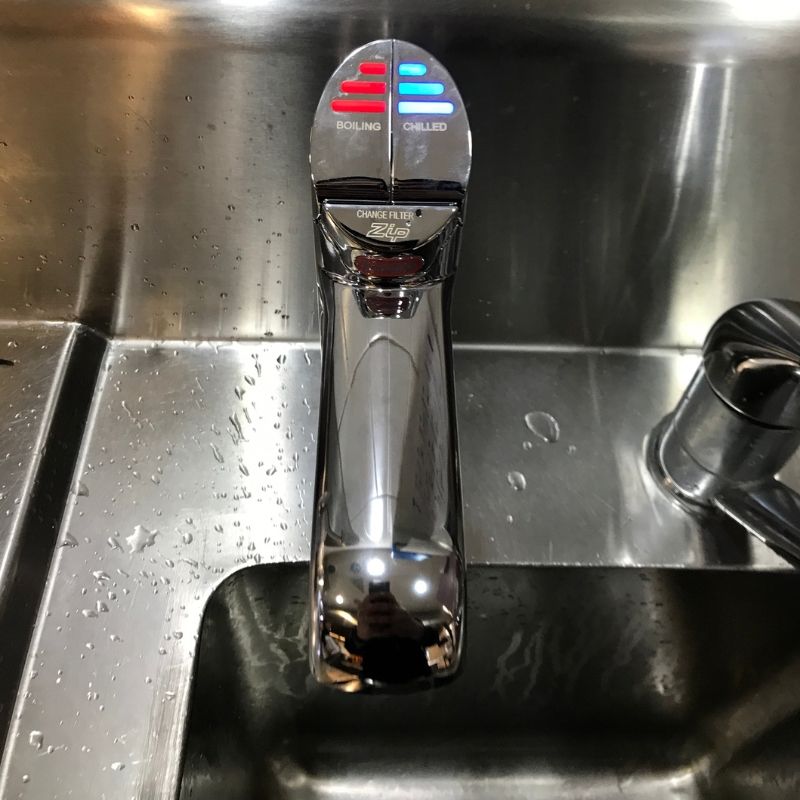 Filtered water tap on a stainless kitchen sink with boiling and chilled buttons