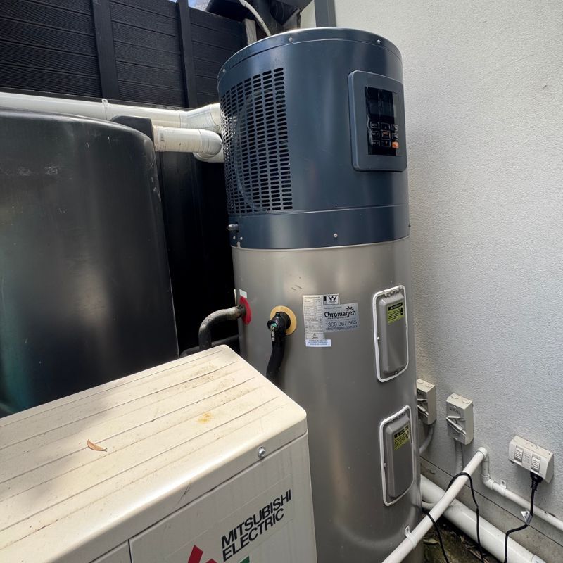 Outdoor hot water system installed beside a house wall with plumbing connections