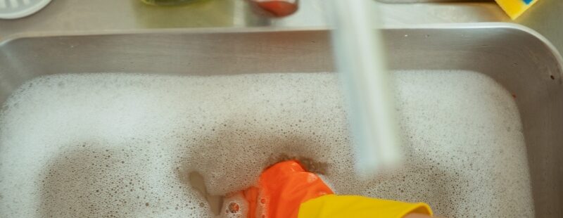 Washing greasy dishes in kitchen sink to prevent Blocked Drains buildup