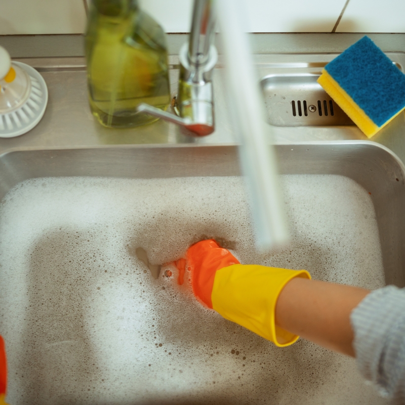 Washing greasy dishes in kitchen sink to prevent Blocked Drains buildup