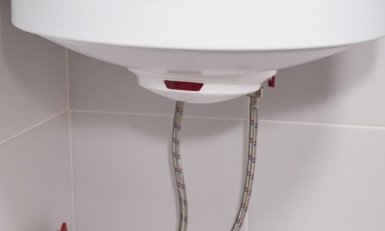 Why Is My Hot Water Suddenly Brown Causes, Quick Checks and When to Call in the Pros Close-up of a modern wall-mounted hot water system showing the bottom base, flexible braided hoses, and valves.